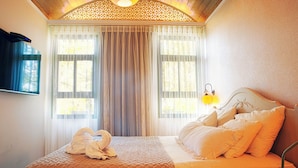 Een hotelkamer met een bed, een aan de muur bevestigde televisie en een raam met gordijnen.