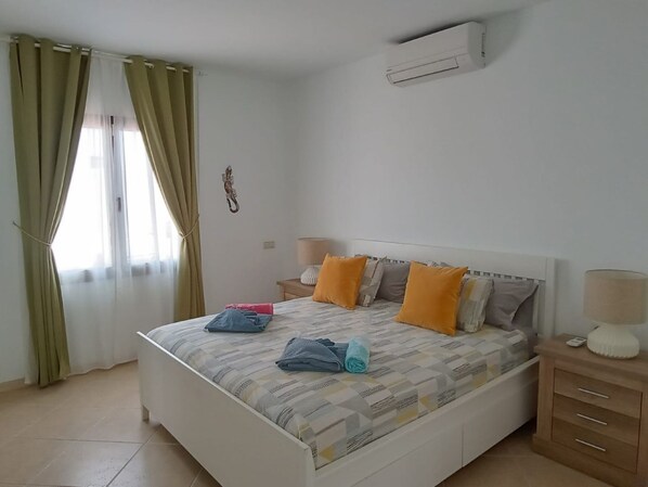 A neatly made bed with pillows and towels, a bedside lamp, and a small table with a lamp. - Beautiful villa with private pool (Playa Blanca)