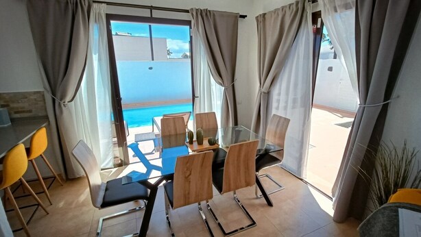 Zona pranzo con tavolo e sedie, vista sul mare e un balcone con tende.