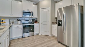 Une cuisine moderne avec des armoires blanches, des appareils en acier inoxydable et un plancher en bois.