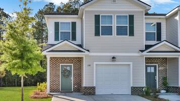 A two-story house with a brick facade, a front garage, and a well-maintained lawn.