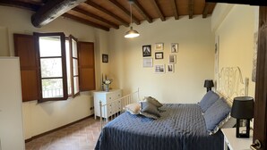 A bedroom with a bed, a nightstand, a dresser, a window with open shutters, and a ceiling with exposed beams. - In the heart of Tuscany, beautiful garden with swimming pool, Casa di Ele awaits you (Gambassi Terme Firenze)