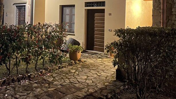 A building with a stone-paved entrance, a small garden with potted plants, and a door with a window above it. - In the heart of Tuscany, beautiful garden with swimming pool, Casa di Ele awaits you (Gambassi Terme Firenze)