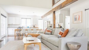 Uma sala de estar moderna com um sofá cinzento, mesa de centro de madeira e uma mesinha lateral metálica.