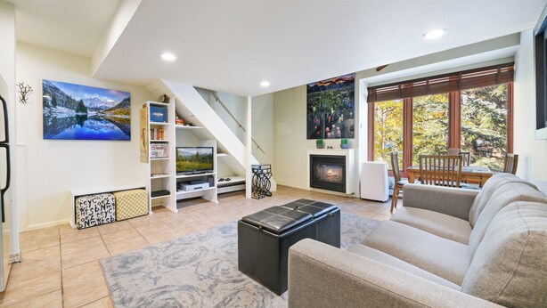 A living room with a sofa, a coffee table, a fireplace, a bookshelf, and a staircase.