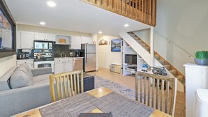 A spacious living area with a dining table, sofa, and kitchen in the background.