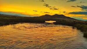 A river reflecting a sunset with a bridge in the background.