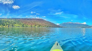 A kayak on a calm lake with a forested mountain in the background.
