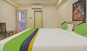 A hotel room with a bed, a chair, a door, and an air conditioning unit.