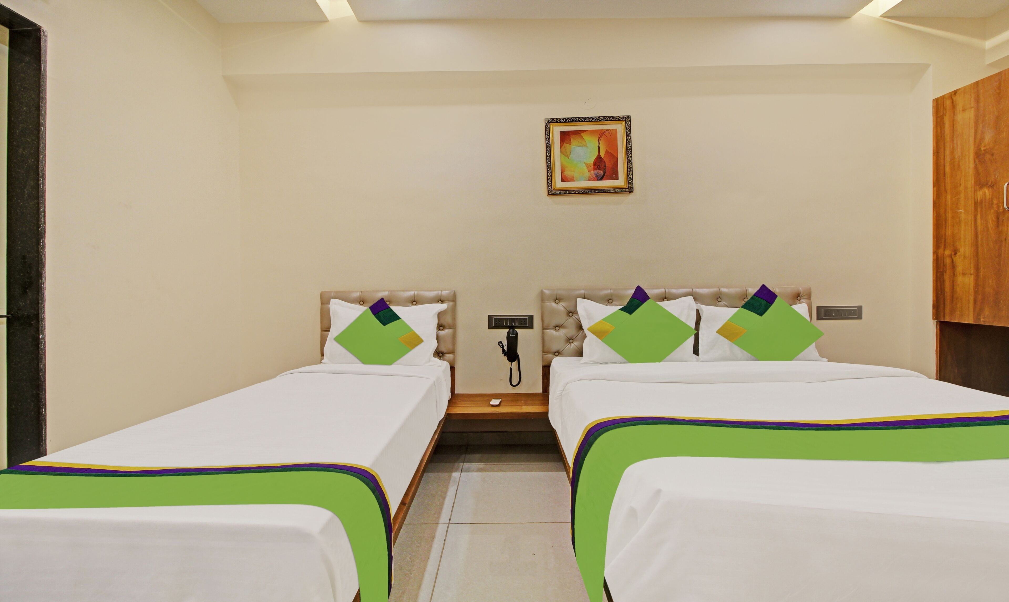 A hotel room with two beds, a telephone, and a painting on the wall.
