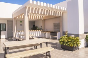 Relax in style with outdoor dining and seating under a pergola, surrounded by lush greenery and comfortable seating.