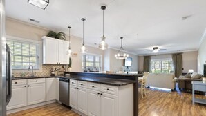 Une cuisine spacieuse avec des meubles blancs, un îlot central et des luminaires suspendus.