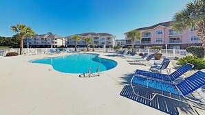 Une piscine avec des chaises longues et une clôture blanche.