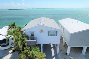 A beachfront property with a white house, a covered dock, and a parked RV.