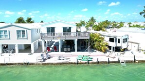 A waterfront property with a covered patio, outdoor seating, and a pool.