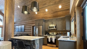 A modern kitchen with granite countertops, stainless steel appliances, and a stone island with bar stools. - Best Mtn/Lake views!!! Lodge on esteemed Lakeside Drive! Hot tub! Fido friendly! (Grand Lake)