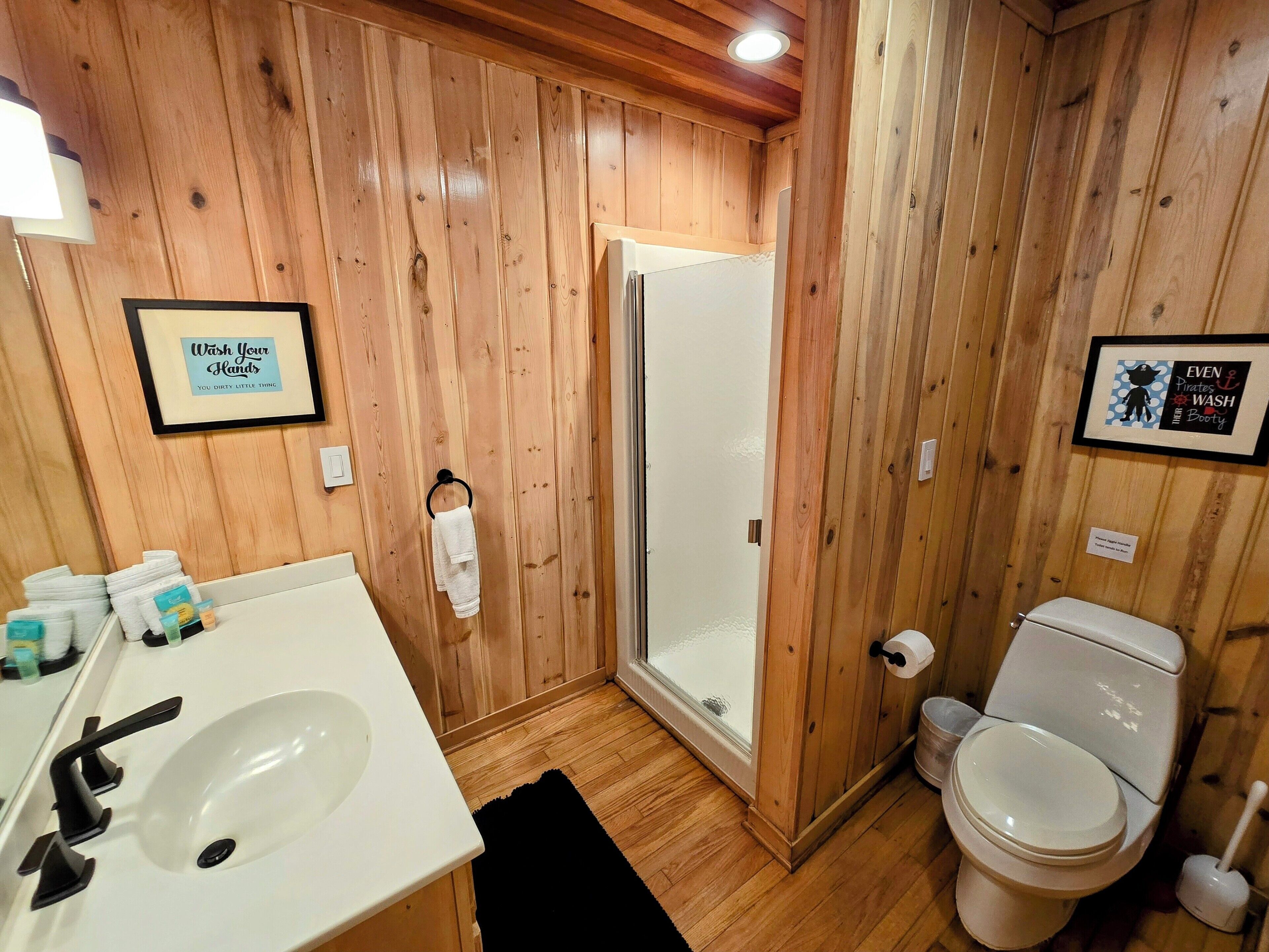 Un baño con paneles de madera, un lavabo, un inodoro y una ducha.