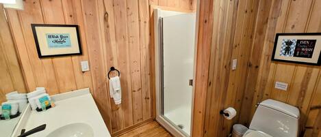 Un baño con paneles de madera, un lavabo, un inodoro y una ducha.