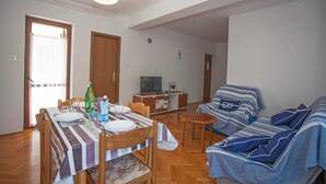 Een woonkamer met een eethoek, een zithoek, een televisie en een houten vloer.