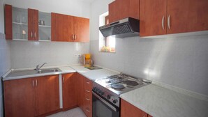 Een keuken met houten kastjes, een gasfornuis, een spoelbak en een raam met uitzicht.