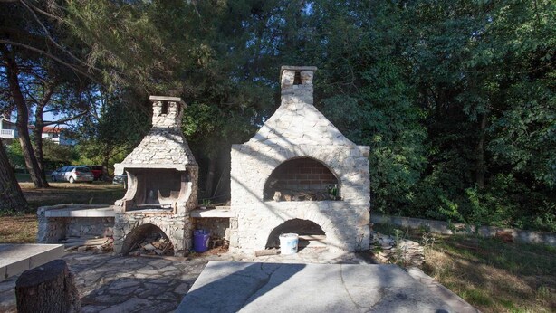A stone-built outdoor structure with a chimney, possibly a fireplace, surrounded by trees. - AGATA Two-Bedroom Apartment 5 (Banjole)