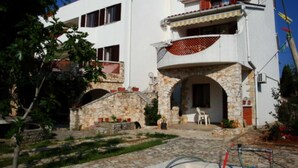 A two-story building with a stone facade, a balcony, and a small entrance with a stone archway. - AGATA Two-Bedroom Apartment 5 (Banjole)