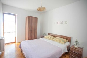A bedroom with a bed, a wardrobe, a bedside table with a lamp, and a wall with the word "HOME". - AGATA Two-Bedroom Apartment 6 (Banjole)