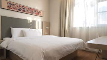 Habitación de hotel con una cama grande, un escritorio, un cabecero y una ventana con cortinas.