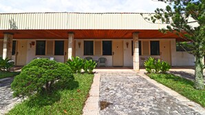 A building with a covered porch, potted plants, and a paved walkway. - Hotel Sampaga by Zuzu (Banjarmasin)