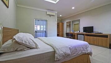 A hotel room with a bed, a desk, a television, and a window with curtains.