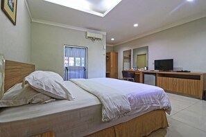 Une chambre d’hôtel avec un lit, un bureau, une télévision et une fenêtre avec des rideaux.