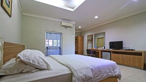 A hotel room with a bed, a desk, a television, and a window with curtains. - Hotel Sampaga by Zuzu (Banjarmasin)