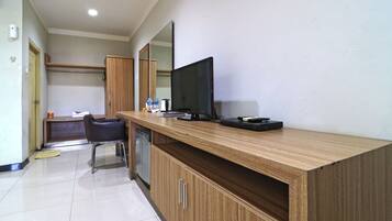 A modern hotel room with a wooden desk, a flat-screen TV, and a mirror.