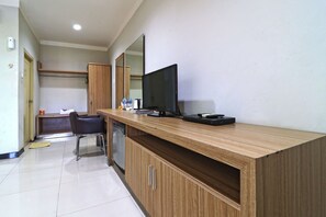 A modern hotel room with a wooden desk, a flat-screen TV, and a mirror. - Hotel Sampaga by Zuzu (Banjarmasin)