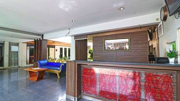 A reception area with a blue sofa, a wooden reception desk, and a red patterned glass partition.