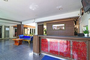 Ein Empfangsbereich mit einer blauen Couch, einem Holztresen und einer dekorativen Glasscheibe.
