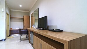 A modern hotel room with a wooden desk, a flat-screen TV, and a mirror. - Hotel Sampaga by Zuzu (Banjarmasin)