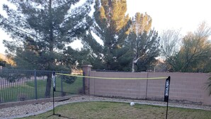 A grassy area with a volleyball net and two goalposts.