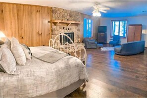 Cozy retreat with a large bed, stone fireplace, and comfortable seating area.