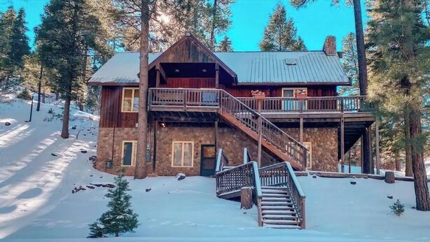 A wooden cabin with a balcony and a staircase leading to the entrance.