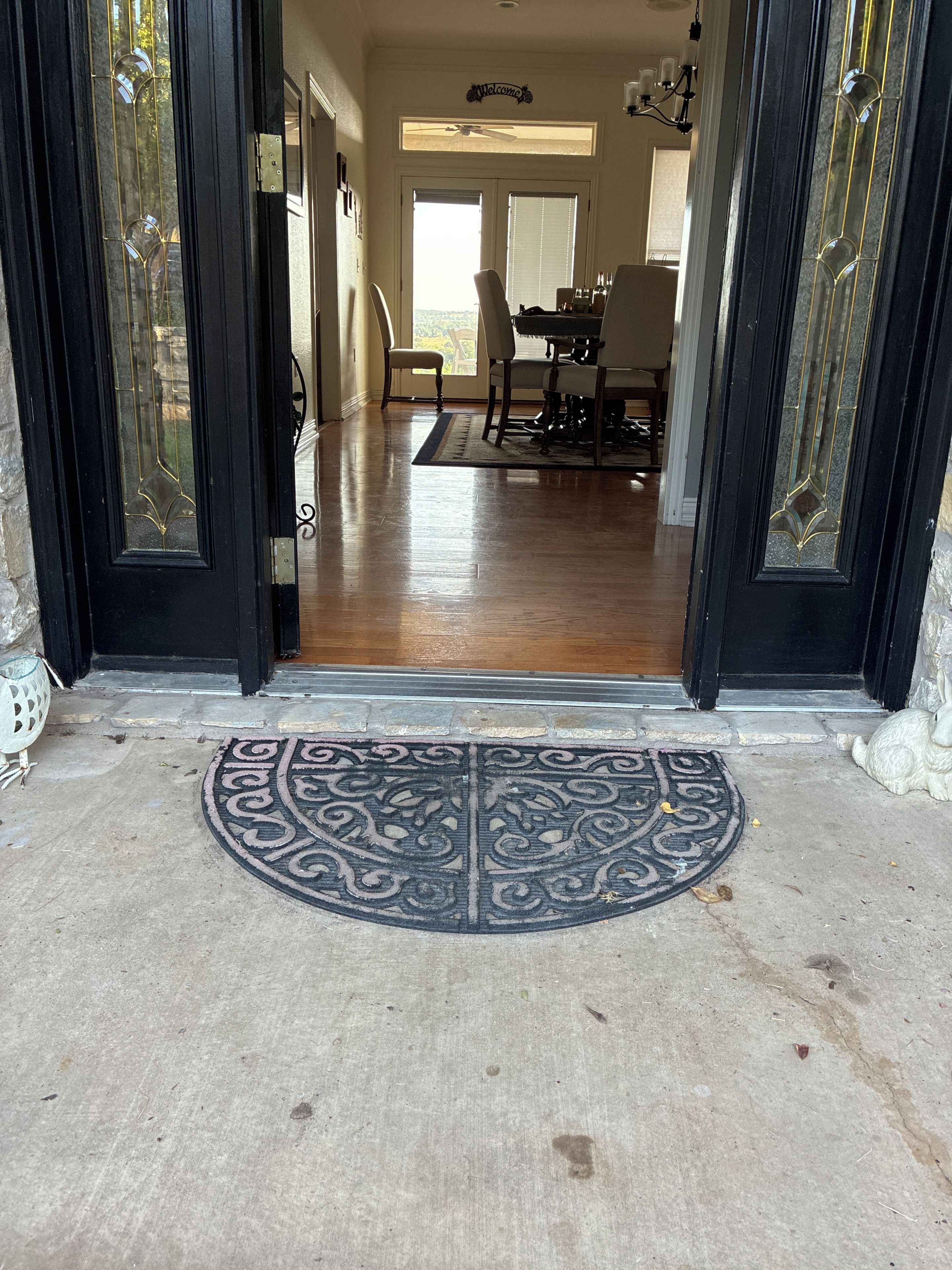 A doorway leading to a dining area with a table and chairs, a ceiling fan, and a welcome sign.