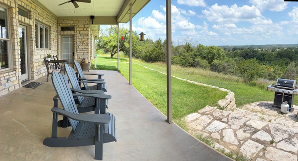 A covered patio with outdoor seating and a stone barbecue area.