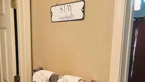 A hallway with a towel rack holding two towels, a sign that reads "STAY relaxed", and a partially visible door.