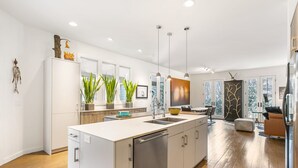 Una cocina moderna con una isla grande, electrodomésticos de acero inoxidable y vistas al exterior a través de amplias ventanas.