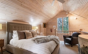 A cozy bedroom with a large bed, a chair, and a view of the outdoors through a window. - The Sanctuary at Deer Dune, Saugatuck, Beautifully stylish, Beautifully relaxing (Saugatuck)