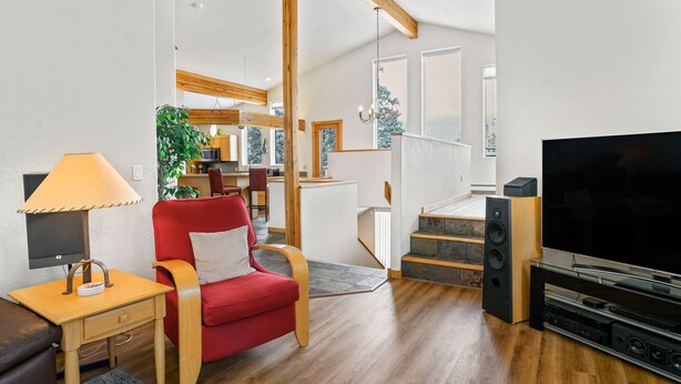 Ein modernes Wohnzimmer mit einem roten Sofa, Holzboden, einem Fernseher und einer Treppe zu einer weiteren Ebene.