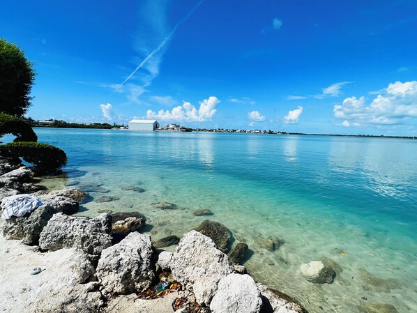 A clear coastal view with rocky shoreline, a distant building, and a clear sky. - Beach House - Waterfront Villa - Free Kayaks (Duck Key)