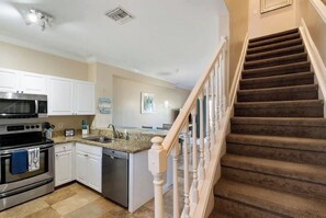 A kitchen with white cabinets, a microwave, an oven, and a dishwasher. There is a staircase with a wooden railing leading to another floor. - Beach House - Waterfront Villa - Free Kayaks (Duck Key)