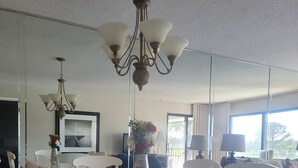 Ein Essbereich mit einem weißen Tisch und Stühlen, einer Chandelüster und einer Vase mit Blumen.