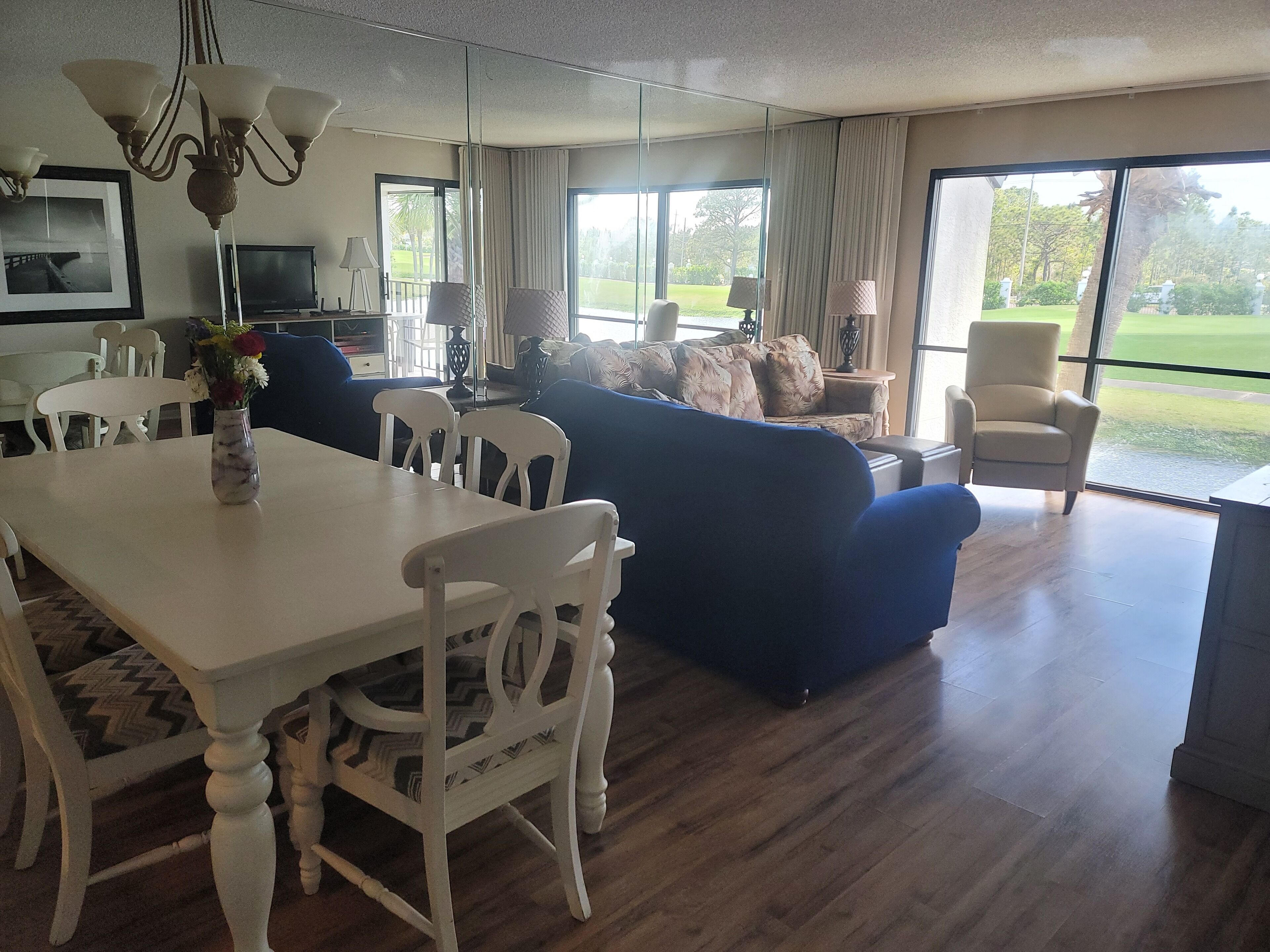 A spacious living room with a dining area, large windows, and a view of the outdoors.